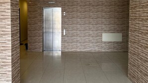 Un hall d’entrée spacieux au design moderne, doté d’un ascenseur central, d’un comptoir de réception et d’un mur orné de motifs.