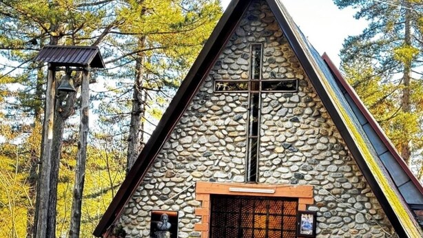 A stone chapel with a cross, a bell tower, and a small statue. - Tranquil apartment in Caprara with stunning views (Caprara)