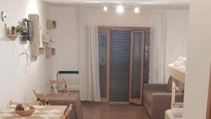 A spacious room with a wooden floor, a dining table with chairs, a sofa, and a bed. - Tranquil apartment in Caprara with stunning views (Caprara)