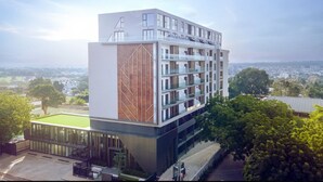 A modern multi-story hotel with a glass facade, a rooftop terrace, and a view of the surrounding landscape. - Snug three-bedroom Unit (Accra)