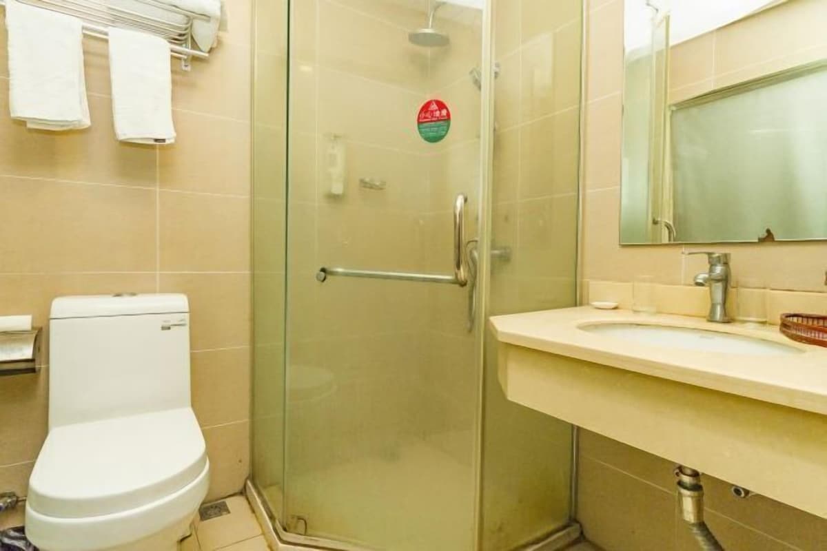 A bathroom with a toilet, a glass shower enclosure, a sink with a mirror, and a towel rack.