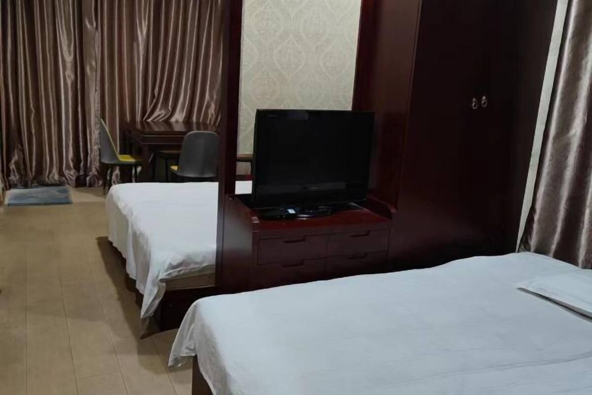 Una habitación de hotel con cama, escritorio con computadora, silla y armario.