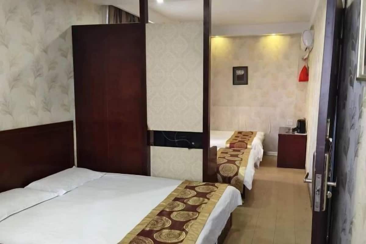 Habitación de hotel con dos camas, cabecero de madera, escritorio pequeño y televisor montado en la pared.