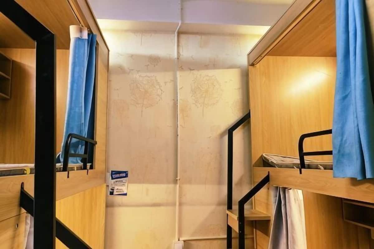 Habitación con literas, techo de madera, cortina azul y un cartel en la pared.