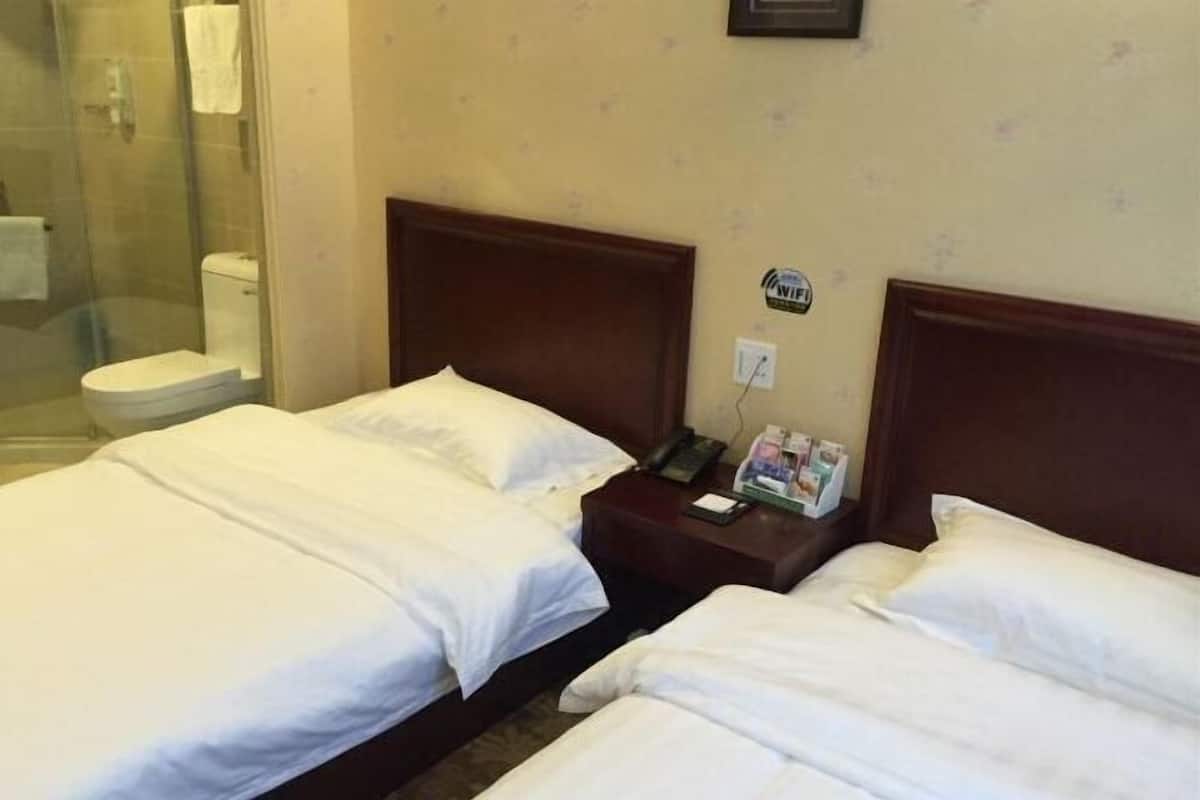 Una habitación de hotel con dos camas, ducha y sanitario.