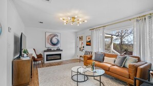 A modern living room with a fireplace, leather sofa, and a glass coffee table.
