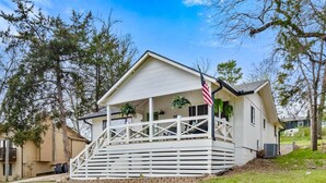 A single-story house with a porch, an American flag, and a small garden area.