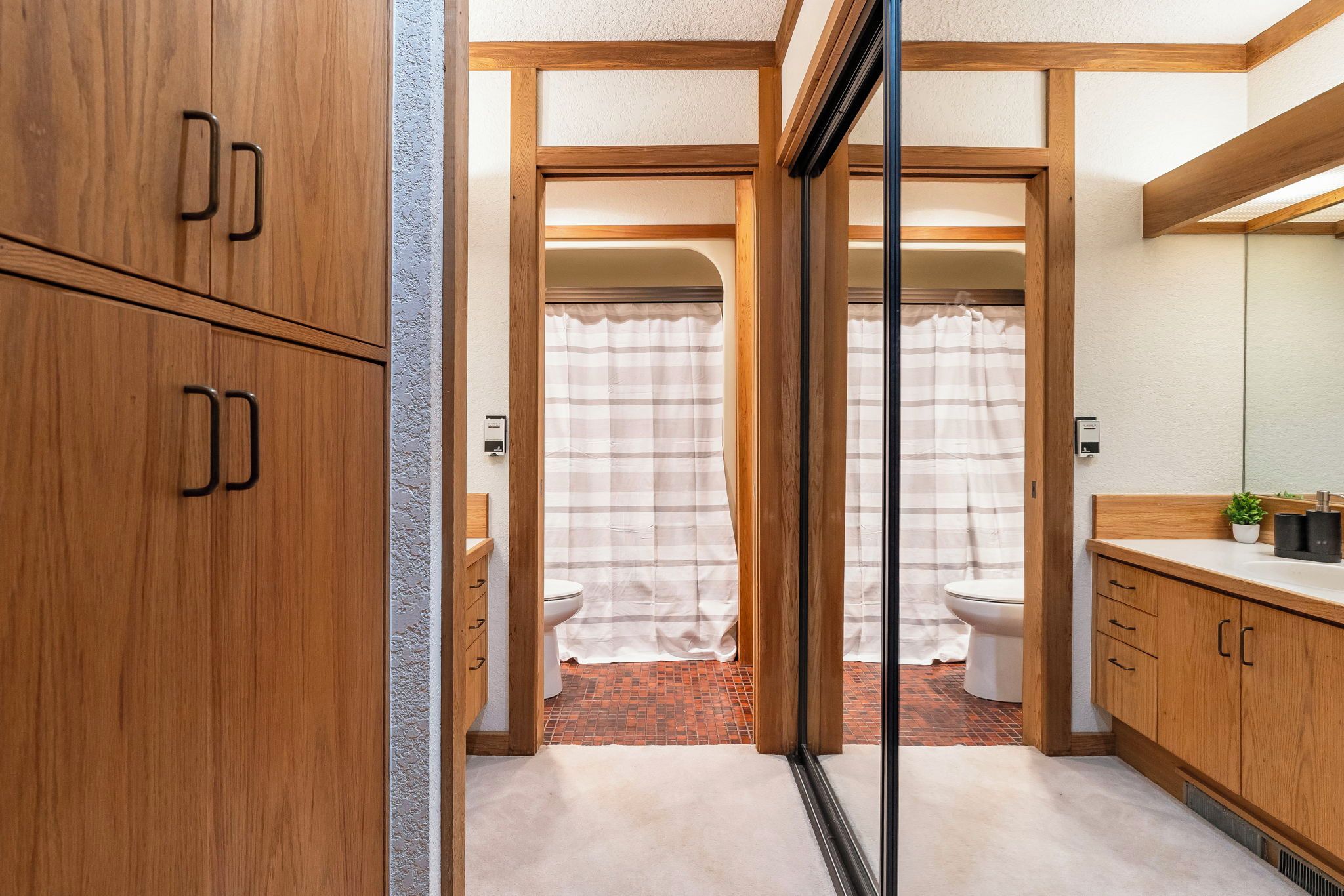 Une petite salle de bain avec des meubles en bois, un rideau de douche et des toilettes.