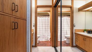 Une petite salle de bain avec des meubles en bois, un rideau de douche et des toilettes.