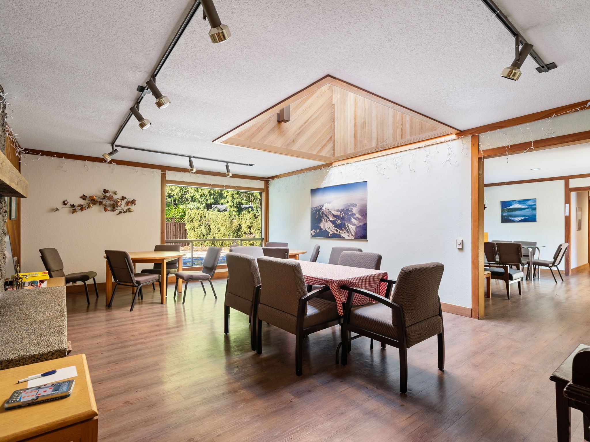 Um quarto espaçoso com uma grande mesa de jantar, várias cadeiras e vista para o exterior através de uma janela ampla.