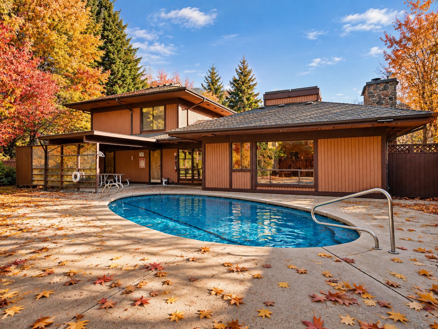 Uma casa moderna com piscina, rodeada por folhas de outono.