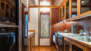 A compact kitchen with wooden cabinets, a window, and a brick backsplash.