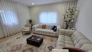 Una sala de estar con sofá, sillón, mesa de centro y plantas decorativas.