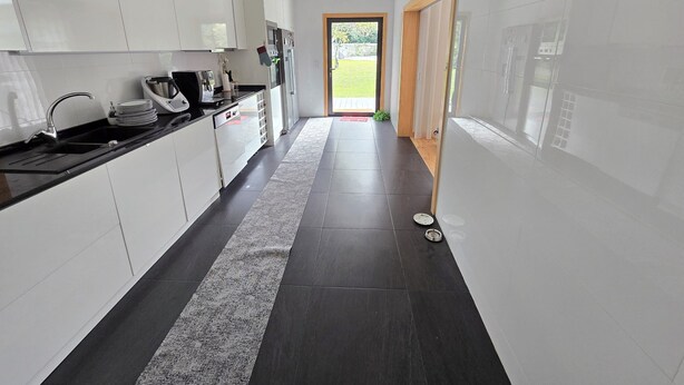 Una cocina moderna con armarios blancos, encimera negra y alfombra blanco y negro.