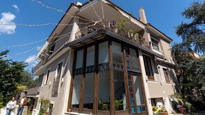 Een huis met twee verdiepingen, een balkon, grote ramen en plantenbakken.