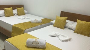 A hotel room with two beds, each with a yellow bedspread and white linens. There is an air conditioning unit on the wall above the beds. - Hotel Roma Urabá (Apartadó)