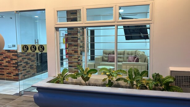 A reception area with a glass door, a brick wall, and a seating area with a sofa and cushions. - Hotel Roma Urabá (Apartadó)