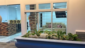 A reception area with a glass door, a brick wall, and a seating area with a sofa and cushions.