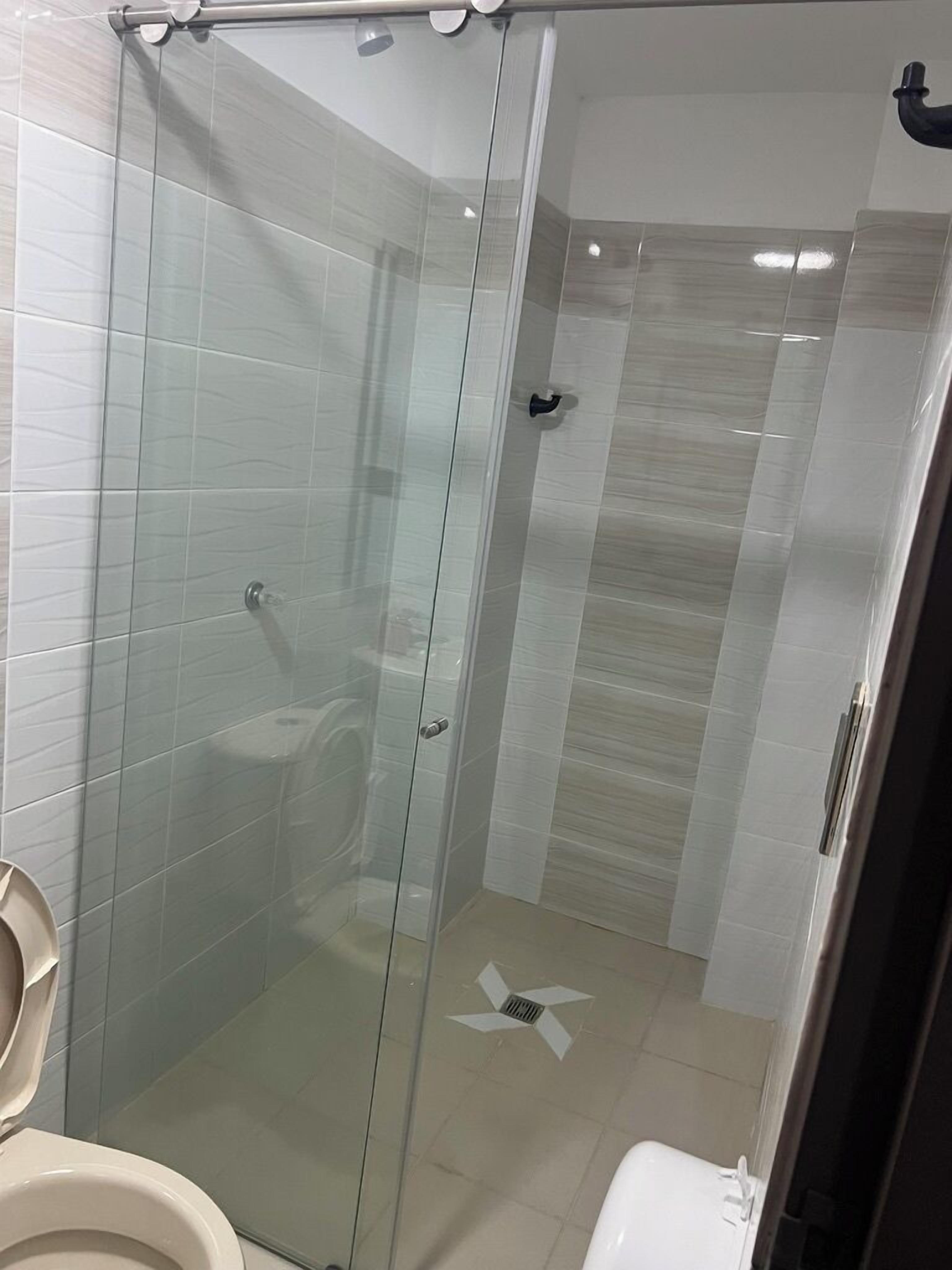 A modern bathroom with a glass shower enclosure, a toilet, and a sink.