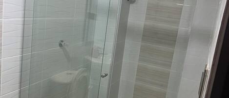 Un baño moderno con cabina de ducha de vidrio, inodoro y lavamanos.