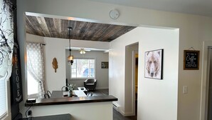 A modern kitchen with a dark countertop, a ceiling fan, and a window with a view of the outside. - Charming 3-bedroom house in Trout Lake close to trails & lakes. (Trout Lake)