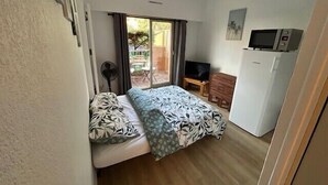 Ein kleines, gemütliches Zimmer mit Bett, Fernseher, Schreibtisch und Kühlschrank.