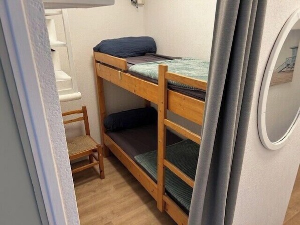 A bunk bed room with a wooden chair and a small table.