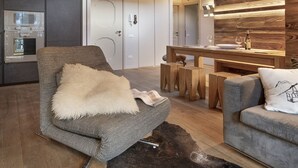 Ein modernes Wohnzimmer mit einem grauen Sessel, einem Holzesstisch und einem grauen Sofa.