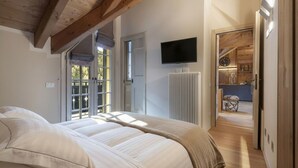 Ein Schlafzimmer mit Bett, Fernseher, Heizkörper und Blick auf eine Holzvertäfelung.