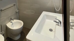 A modern bathroom with a white sink, bidet, and towel rack. - rienzo vatican suites  (Rome)