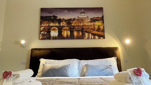 A hotel room with a large bed, two bedside tables, a headboard, and a night sky view of a cityscape. - rienzo vatican suites  (Rome)