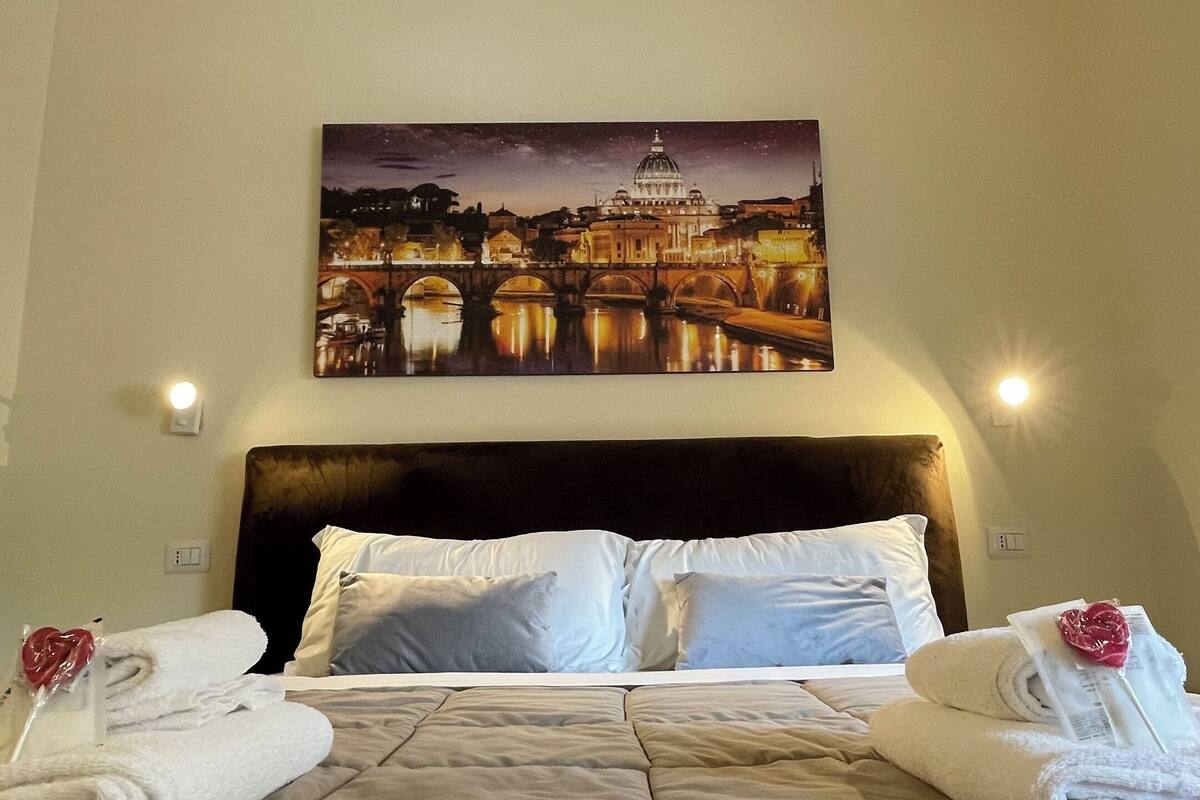 A hotel room with a large bed, two bedside tables, a headboard, and a night sky view of a cityscape.