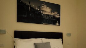 A hotel room with a bed, white bedding, a white towel, and a red lollipop on the towel. - rienzo vatican suites  (Rome)