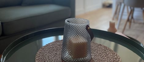 A glass table with a woven placemat and a candle holder.