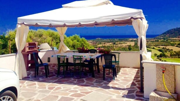 An outdoor patio with a covered table and chairs, a barbecue grill, and a scenic view of the landscape. - APARTMENT WITH SEA VIEW TERRACE (Tanaunella)