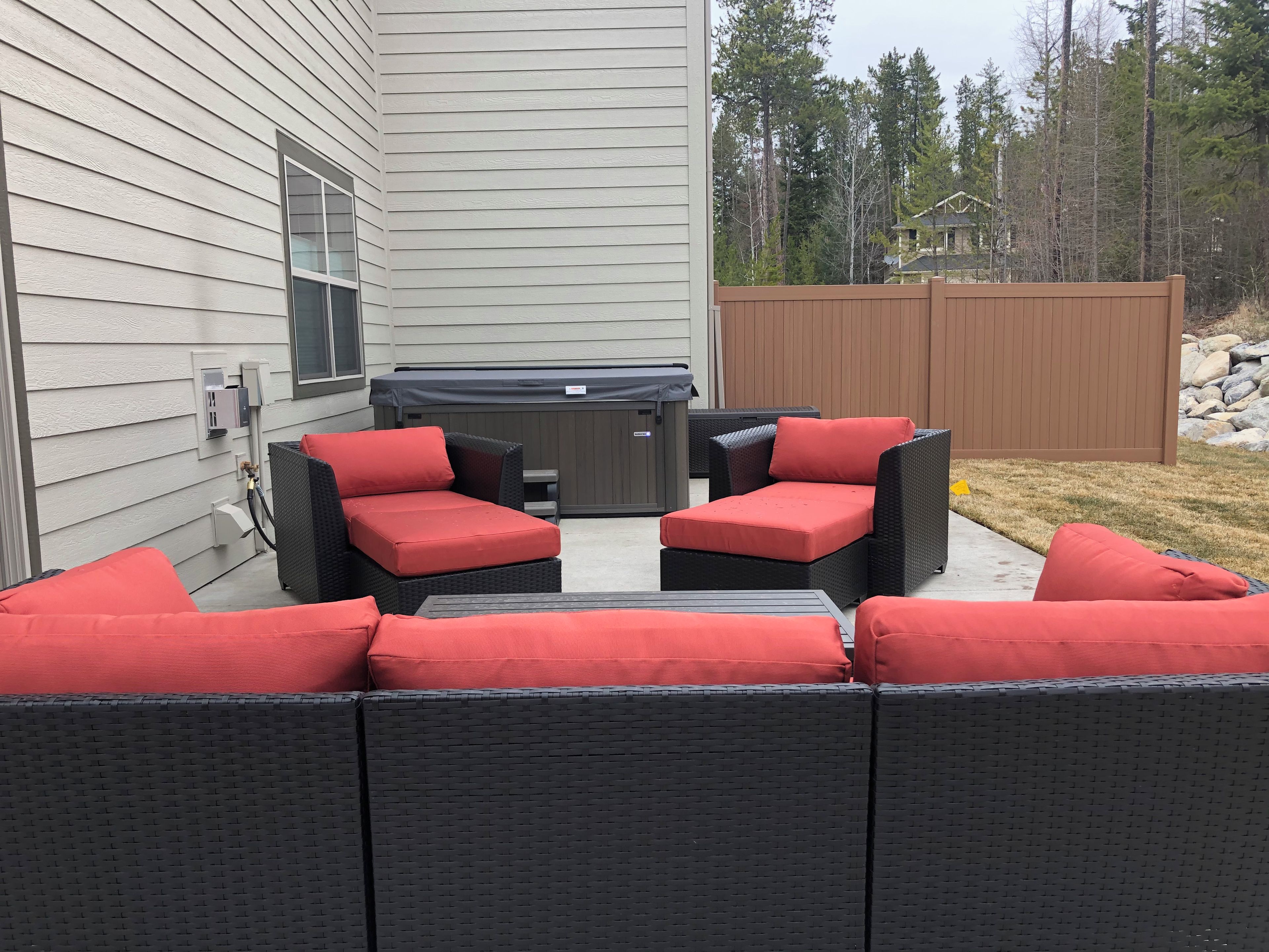 An outdoor seating area with a hot tub and a wooden fence.