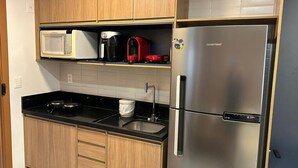 A compact kitchen with a stainless steel refrigerator, a microwave, a coffee maker, and a toaster.