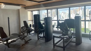 A gym with various exercise equipment, large windows, and a view of a cityscape.