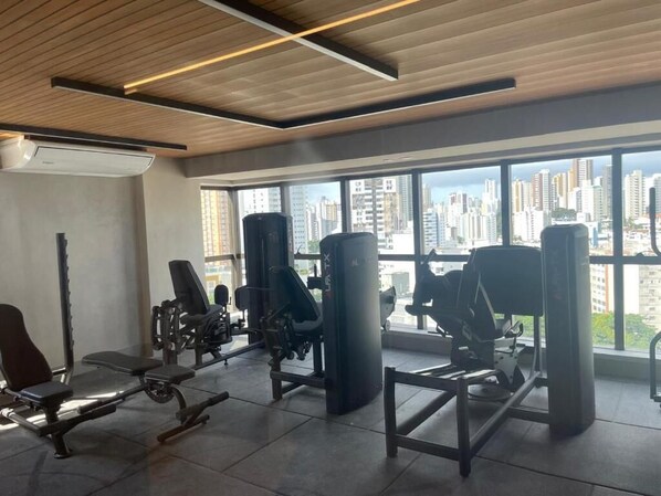 A gym with various exercise equipment, large windows, and a view of a cityscape.