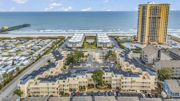 Ein Hotelkomplex an der Küste mit mehreren Gebäuden, einem Parkplatz und Blick auf das Meer.