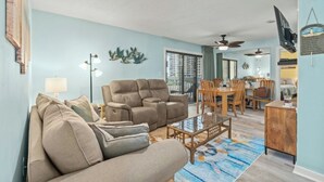 Ein Wohnzimmer mit einer Couch, Sesseln, einem Couchtisch und einem Essbereich mit Stühlen und einem Tisch.