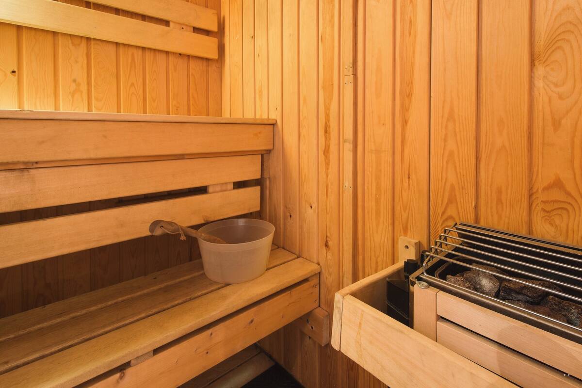 Una sauna de madera con bancos y un estante metálico para objetos.