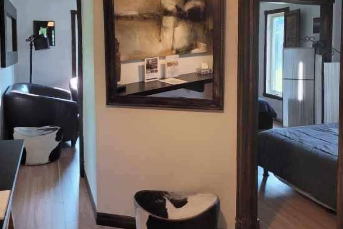 Una habitación moderna con un espejo grande, un sofá, una mesa de centro y una cama.