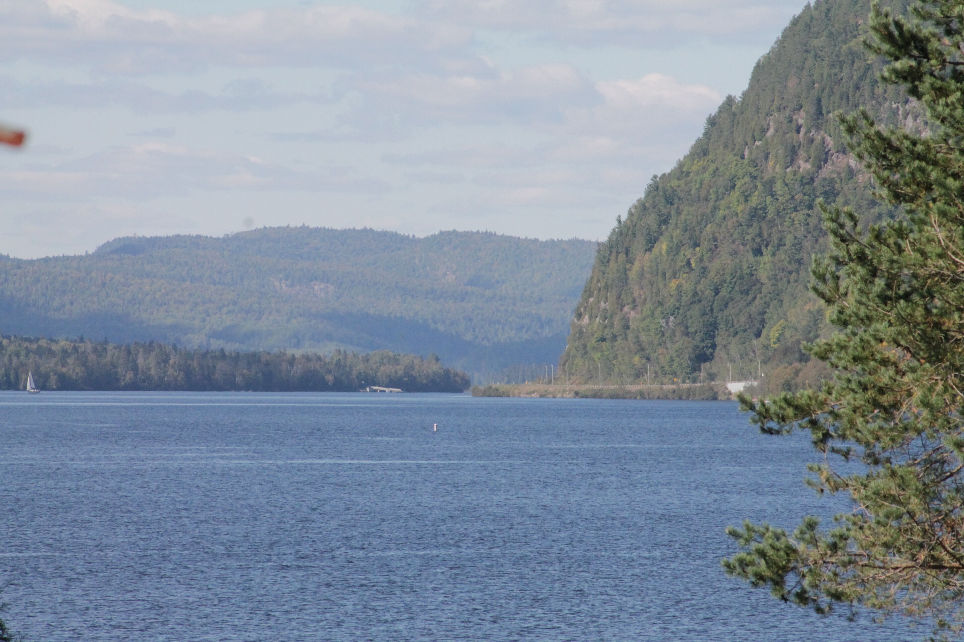 A calm lake with a forested mountain in the background.