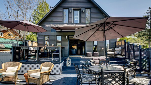 Een huis met een patio, voorzien van tuinmeubilair en parasols.