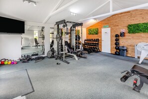 A gym with weightlifting equipment, a mirror, and a wall-mounted fire exit sign. - 3 Bed in Broadwoodwidger (oc-s31783) (Broadwoodwidger)