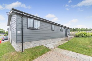 A single-story mobile home with a stone foundation, a front porch, and a small front yard.