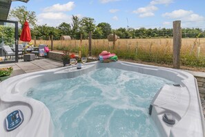 A hot tub with a control panel, surrounded by outdoor furniture and a view of a field. - 3 Bed in Broadwoodwidger (oc-h31771) (Broadwoodwidger)
