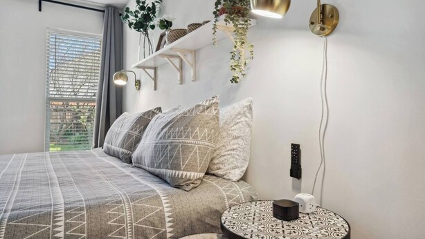 Un dormitorio moderno con cama, mesita de noche y una lámpara de pared.