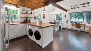 A modern kitchen with a central island, built-in appliances, and wooden beams. - Lakefront | Hot Tub | Kayaks | High End | Peaceful (Tobyhanna)
